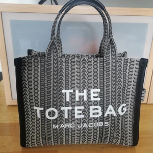 Marc Jacobs The Tote bag small - Populär Marc Jacobs väska i en snygg design. Inköpt på Nordstrom i USA där äkthetsbevis följer med och kvitto finns. ﻿﻿Knappt använd, som nyskick. ﻿﻿Väskan är rymlig och med ett praktiskt fack med dragkedja inuti samt två mindre fack. En avtagbar axelrem medföljer också (som är ny). Väskans mått är ca 30x23x13 cm. 🤩🤩