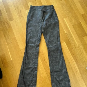 Gråa bootcut byxor i mockaimitation - Helt nya! Riktiga priset: 500kr Snygga gråa bootcut byxor i mockaimitation med hög midja. Byxorna har en lätt marmorerad look och stängs med dold dragkedja fram. Perfekta för dig som vill ha en trendig och unik stil.