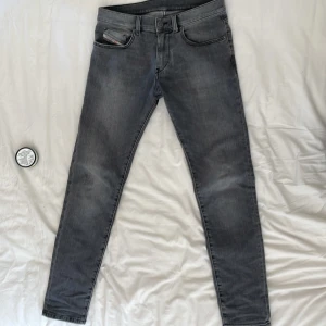 Grå Diesel Larkee jeans - Säljer ett par grå Diesel Larkee jeans med klassisk femficksdesign och snygga slitningar. Jeansen har normal passform och raka ben, med Diesel-logga på bakfickan och patch i läder baktill. Perfekta för dig som gillar en avslappnad men stilren look.