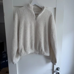 Beige fleece half zip tröja - Supermjuk och fluffig beige fleece-tröja med half zip och hög krage. Perfekt för kyliga dagar, med långärmad passform och avslappnad stil. Materialet är riktigt gosigt och håller dig varm hela hösten och vintern.