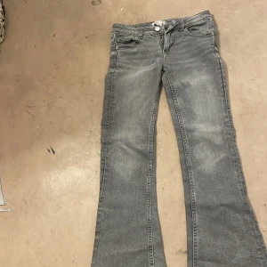 Grå bootcut jeans från Gina Tricot - Snygga grå jeans från Gina Tricot i bootcut-modell. Jeansen har klassisk femficksdesign, normal passform och är tillverkade i mjukt jeanstyg. Perfekta för dig som gillar en avslappnad men trendig look.