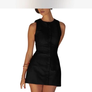 Ärmlös miniklänning med knappar - Supersnygg ärmlös miniklänning med knappar framtill och markerad midja. I färgen svart med en enkel och stilren design. Klänningen har en lätt utställd kjol och bälte bak på den röda varianten. Perfekt för dig som gillar minimalistisk stil. Bara svart, den röda är bara till för att visa ryggen! 🥰