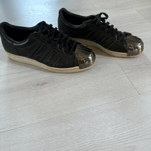 Adidas superstar - Svarta adidas superstars med metallfront  storlek 40 passar upp till 42 (jag har 42). köpta på secondhand för 500, kommer inte längre till användning men är helt okej skick.