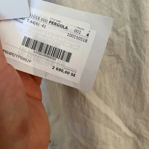 Vit vindjacka från Max Mara Leisure - Snygg vit vindjacka från Max Mara Leisure med huva, svarta snören och halv dragkedja. Jackan har en stor ficka framtill och elastiska muddar vid ärmsluten. Perfekt för dig som gillar stilren och sportig look.