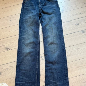Mörkblå raka jeans från Zara - Snygga mörkblå jeans från Zara med raka ben och klassisk femficksdesign. Jeansen har knäppning med knappar och är tillverkade i robust denim. Perfekta för en avslappnad och stilren look.