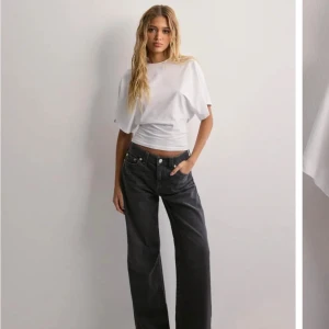 Söt topp från Nelly - Säljer en vit  topp från Nelly med breda, korta ärmar och tight passform i midjan. Toppen har en enkel och clean look, perfekt att styla med jeans eller kjol. Tillverkad i mjuk bomull som känns skön mot huden.