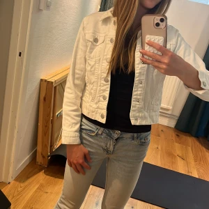 Vit jeansjacka - Vit jeansjacka för barn. Jackan har knappar framtill och två bröstfickor med knapp. Perfekt för vår och sommar. 