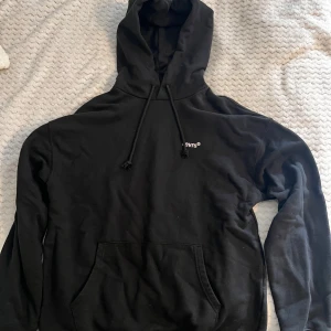 Svart hoodie från Levi's med huva - Svart hoodie från Levi's i avslappnad passform med huva och snörning. Klassisk känguruficka framtill och liten vit Levi's-logga på bröstet. Perfekt för dig som gillar en enkel och stilren look. Tillverkad i mjuk bomull för extra komfort extremt behaglig för hemmabruk men även stil ren för utomhusbruk. Vid eventuella funderingar är det bara skriva!