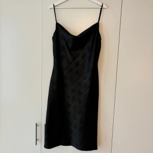 Urban Outfitters slipklänning - Skön och smickrande svart slipklänning från urban outfitters i märket ”Kiss the Sky”. Sitter fint på kroppen med spaghettiband på ryggen som gör att du kan justera både längd över axlarna och bredd över bröstkorgen. Fint svart mönster och sitter normal i storleken🖤använd endast en gång
