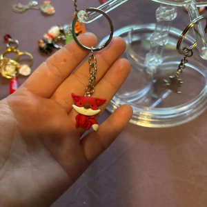 Nyckelring med röd rävfigur - Söt nyckelring med en liten röd räv i mjukt material. Räven har vita detaljer på svansen och ansiktet samt en brun nos. Perfekt att hänga på väskan eller nyckelknippan för en gullig touch.