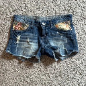Blå jeansshorts med brodering - Snygga blå jeansshorts med slitna detaljer och broderingar. Lappen står stradivarius 34/36