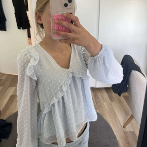 Ljusblå blus från Gina Tricot - Supersöt ljusblå blus från Gina Tricot med prickigt mönster, volangdetaljer och v-ringning. Blusen har långa, luftiga ärmar och en flowy passform. Perfekt för vår och sommar när du vill känna dig extra fin! Tröjan är använd få gånger nästan ny och priset går att diskuteras!🥰🥰