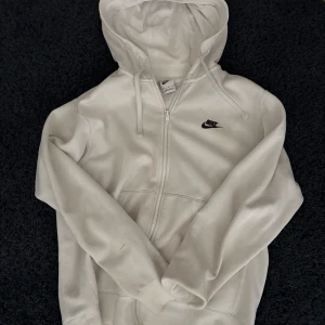 Vit hoodie från Nike med dragkedja - Snygg vit hoodie från Nike med svart logga på bröstet. 