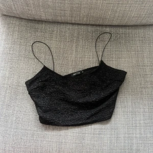 Svart croppad linnetopp  - Säljer en svart croppad linnetopp med tunna axelband och lätt glittrig struktur. Perfekt för att lyfta en outfit med sin stilrena och trendiga look 💕