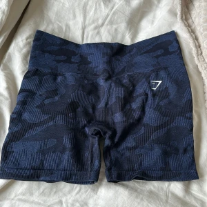 Gymshark shorts - Mörkblå camo shorts från gymshark, lite noppriga på baksidan som syns på bilderna, annars perfekt skick! Gissar på storlek S