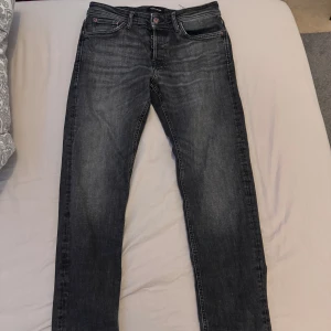 Mörk gråa jeans från Jack & Jones - Snygga mörk gråa  jeans från Jack & Jones med klassisk femficksdesign och knappgylf. Jeansen har en något tvättad look och raka ben. Perfekta till vardags för en stilren och avslappnad outfit. Storlek W30/L30