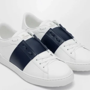 Valentino Garavani Open sneakers vit/marin - Snygga Valentino Garavani Open sneakers i vitt skinn med bred marinblå läderdetalj över vristen. Klassisk rund tå, vita snören och diskret logga på plösen. Sulan är vit med nitar baktill för en cool touch. Perfekta för dig som gillar stilrena och exklusiva sneakers.