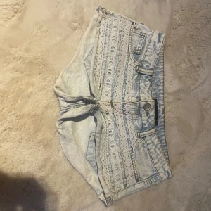 Ljusblå Tally Weijl Jeanshorts - Säljer ett par ljusblå jeansshorts med snygga spets- och broderidetaljer framtill. Shortsen har låg midja, klassiska fickor och knappstängning. Perfekta för sommaren!!❤️