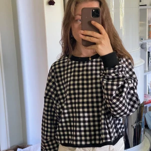 Svartvit rutig croppad tröja - Säljer en croppad långärmad tröja med svartvitt rutigt mönster. Lätt och tunnt men inte genomskinligt material. Knappt använd.