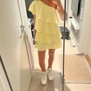 Zara Gul volangklänning  - Superfin ljusgul kortklänning med flera volanger och en oneshoulder-design som passar perfekt till skolavslutningen! Klänningen är i mycket gott skick, utan några som helst defekter och använd endast 2 gånger. Skriv gärna vid fler frågor❤️