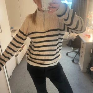 Randig stickad tröja med dragkedja - Säljer en beige och svart stickad tröja med halv dragkedja i halsen.Knappt använd men haft länge.Pris går att diskutera💕