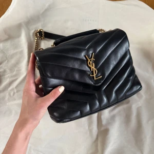 YSL loulou medium - Säljer min fina YSL lou lou väska i medium. Svart läder med guld hardware. Inköpt 2022 i YSL butiken i Köpenhamn. Den är i superfint skick. Kommer med dustbag, box, äkthetsintyg och kvitto. Finns att hämta i Göteborg. Säljer endast vid avhämtning, skickar alltså inte.   Nypris 30 000 kr.
