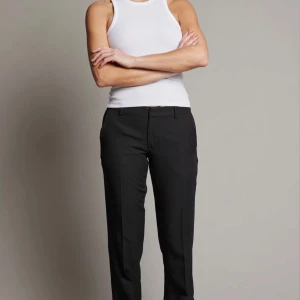 Svarta kostymbyxor med rak passform - Snygga svarta kostymbyxor med klassisk rak passform och låg midja. Byxorna har diskreta fickor och stängs med dragkedja och knapp. Perfekta för en stilren look.