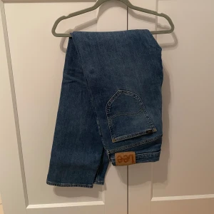 Blå jeans från Lee - Snygga blå jeans från Lee med klassisk femficksdesign. De har en rak passform och är perfekta för en avslappnad stil. Jeansen har en diskret Lee-logga på bakfickan och är tillverkade i slitstarkt denim.| Storlek 30/32| Dem är helt oanvänd! Bara att höra av sig vid frågor! Nypris:1300kr, Har även ett exakt likadant par ute i samma storlek fast i en mörkare blå om man vill köpa båda tillsammans till ett mycket bra pris!