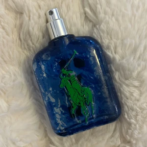 Ralph Lauren Big Pony Blue Eau de Toilette - Fräsch herrparfym från Ralph Lauren Big Pony Collection. Flaskan är blå med en grön polospelare på framsidan och har en silverfärgad spraykork. Doften är sportig och energisk, perfekt för dig som gillar en modern och maskulin stil.