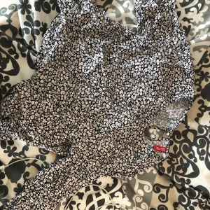 Blommig blus från H&M Divided - Supersöt blommig blus från H&M Divided i svart med små vita och ljusrosa blommor. Luftig modell, perfekt för varma dagar. Tunt och skönt material som känns lätt mot huden. Snygg att matcha med jeans eller kjol!