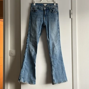 Blå bootcut jeans  - Snygga ljusblå midwaist bootcut jeans med fransad kant nertill. Jeansen är lite stretchiga och sitter jätteskönt. Skriv till mig vid frågor eller funderingar😊                                                   Midjemått rakt över: 36cm                                               Innerbenslängden: 74cm
