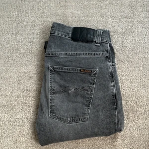 Grå Nudie Jeans - Tja! Säljer nu dessa feta Nudie Jeans! De är i riktigt bra skick, skulle säga 9/10, eftersom denne knappt använda! Storleken är W 32 och L 32. Nypris: 1499kr‼️❌ Mitt pris: 499kr✅ Skriv gärna vid fler frågor och pris kan diskuteras!🤝
