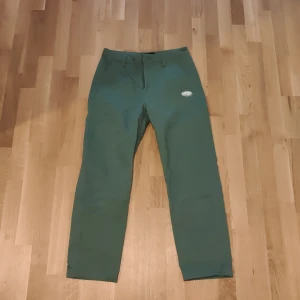 Gröna byxor med broderade djurmotiv - Säljer ett par gröna byxor med unika broderade djurmotiv över hela tyget. Byxorna har normal passform och stängs med dragkedja och knapp. Perfekta för dig som vill ha något annorlunda och lekfullt i garderoben.