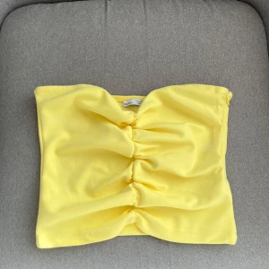 Gul tubtopp från Bershka - Säljer en gul tubtopp från Bershka med rynkade detaljer framtill och dragkedja i sidan. Använd max 2 ggr, storlek S🥰 kom gärna med prisförslag!