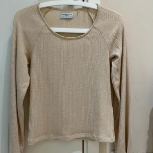 Beige ribbad långärmad tröja från Holly & White - Säljer en beige ribbad långärmad tröja från Holly & White. Tröjan har en rund halsringning och är tillverkad i ett mjukt material som passar perfekt för lager-på-lager. Enkel och stilren design som funkar till mycket. Ny utan prislapp 