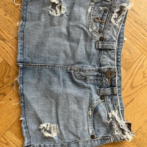 Mini jeanskjol - Snygg ljusblå jeanskjol från Top shop med slitna detaljer och råa kanter. Kjolen har flera fickor med knappar både fram och bak samt coola bälteshällor. 