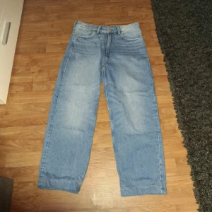 Blå loose fit jeans från H&M - Säljer ett par ljusblå jeans från H&M med loose fit. Jeansen har klassisk femficksdesign, raka ben och normal midja. Perfekta för en avslappnad stil och passar till det mesta. Snygg tvätt och bekvämt material. OBS! JAG HAR KORYAT NER BYXORNA (KOLLA SISTA BILD) FRÅGA OM MÅTT!