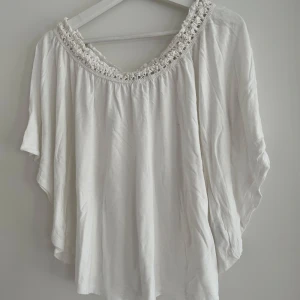 Off shoulder topp med virkad kant Gina Tricot - Off shoulder topp från Gina Tricot med bred, virkad kant runt halsen. Modellen är lös och luftig. Perfekt för varma dagar och ger en bohemisk känsla till din outfit.