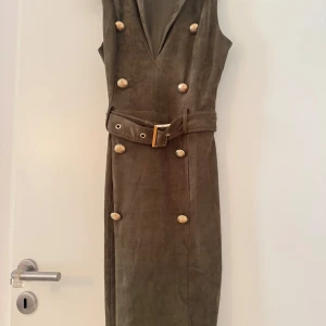 Olivgrön ärmlös klänning med bälte - Snygg olivgrön långklänning i mockaimitation med djup v-ringning, använt 2-3 gånger 