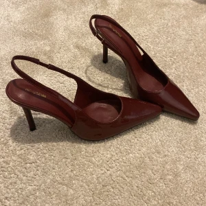 Vinröda pumps med spetsig tå - Snygga vinröda pumps från PrettyLittleThing med smal klack och spetsig tå. Skorna har öppen häl med justerbar rem och är tillverkade i glansigt syntetmaterial. Perfekta för dig som vill sticka ut med en elegant och trendig look. Tycker dom är skiiiiitsnygga men har aldrig använt då jag tycker dom är för höga för mig. 