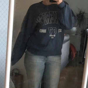 Mörkblå oversized sweatshirt - Säljer en mörkblå oversized sweatshirt med tryck i vitt och beige framtill. Tröjan har rund hals och långa ärmar, perfekt för en chill och avslappnad stil. Passar dig som gillar collegevibbar och streetwear.