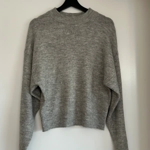 Grå stickad tröja från H&M - Mysig grå stickad tröja från H&M med rund halsringning och långa ärmar. 