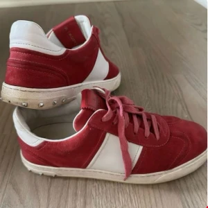 Röda och vita sneakers från Valentino - Säljer ett par snygga röda och vita sneakers från Valentino med klassisk design. Skorna har vita detaljer och små nitar på hälen. Perfekta för dig som vill ha något unikt och stilrent i garderoben.