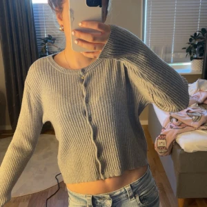 Grå ribbad kofta - Säljer en ljusgrå ribbstickade koftan. JÄTTEFIN!!💗💗Perfekt till jeans eller kjol. Har ett liten hål på armen men inget som märks av