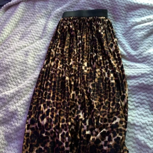 Leopardmönstrad kjol från JDY - Säljer en snygg leopardmönstrad kjol från JDY med svart resår i midjan. Kjolen är lång och har ett plisserat tyg som ger ett coolt fall. 