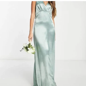 Ljusgrön långklänning i satin - Säljer en elegant LJUDSGRÖN lågklänning i satin med v-ringning och ärmlös design. Prislappen är kvar. Klänningen har omlott-detalj framtill och en djup v-ringning i ryggen. Perfekt till bal. Fråga gärna om mer bilder 💗 Nypris 600 kr💗