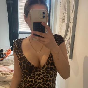 Leopardmönstrad tight klänning - Säljer en leopardmönstrad tight klänning med djup v-ringning och korta ärmar. Klänningen har figurnära passform och är perfekt för dig som vill sticka ut. Materialet känns mjukt och följsamt mot kroppen.