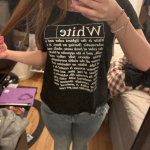 Svart t-shirt med vit text - Cool svart t-shirt med stor vit text och tryck framtill. T-shirten har en klassisk passform och korta ärmar. Perfekt för dig som gillar statement-plagg och enkel stil.