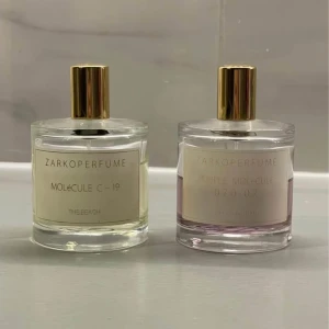 Zarkoperfume - Zarkoperfume Molecule ”The Beach”  C-19 och Purple Molecule. Två exklusiva parfymer från Zarkoperfume: Molecule C-19 med transparent vätska och Purple Molecule 070 07 med ljuslila ton. Båda flaskorna har rund form, genomskinligt glas och eleganta guldfärgade lock.
