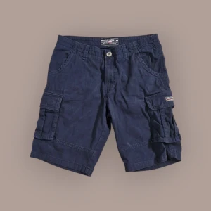 Mörkblå cargoshorts från Polo Club - Mörkblå cargoshorts från Polo Club med flera praktiska fickor på sidorna och knappstängning i midjan. Klassisk design med normal passform, perfekta för varma dagar. Snygga detaljer och robust bomullsmaterial.